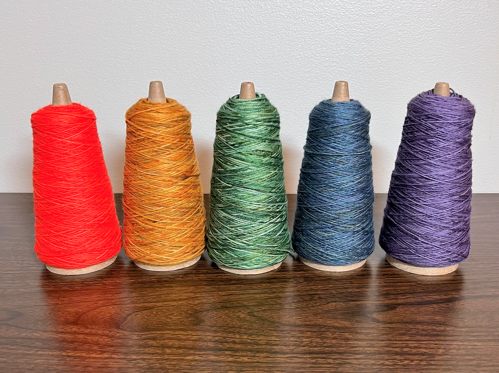 5 wound cones of yarn, varying color